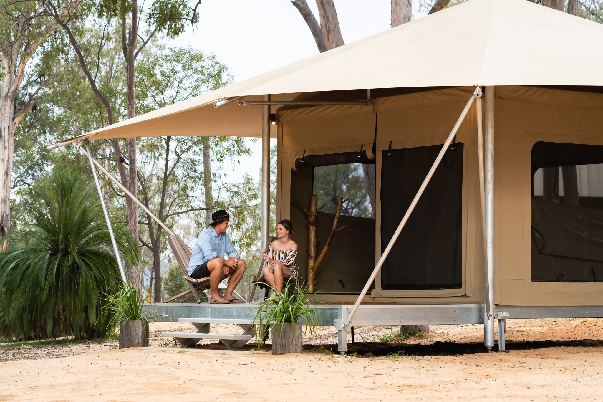 Wallaroo Outback Retreat glamping tent exterior. Two guests sitting on patio in the bushland setting