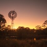 A windmill and shadowed by a sunset