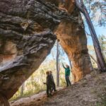 Three people looking up at the underside of a naturally made rock arch