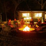 A group of people relaxing around a campfire at night