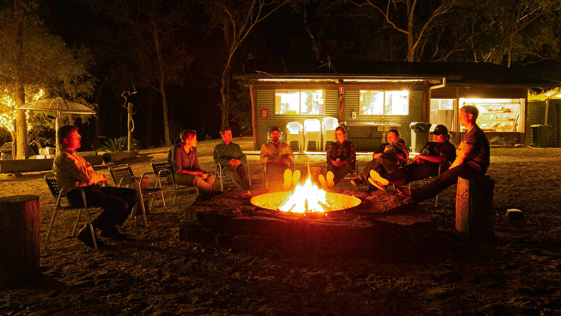 A group of people relaxing around a campfire at night