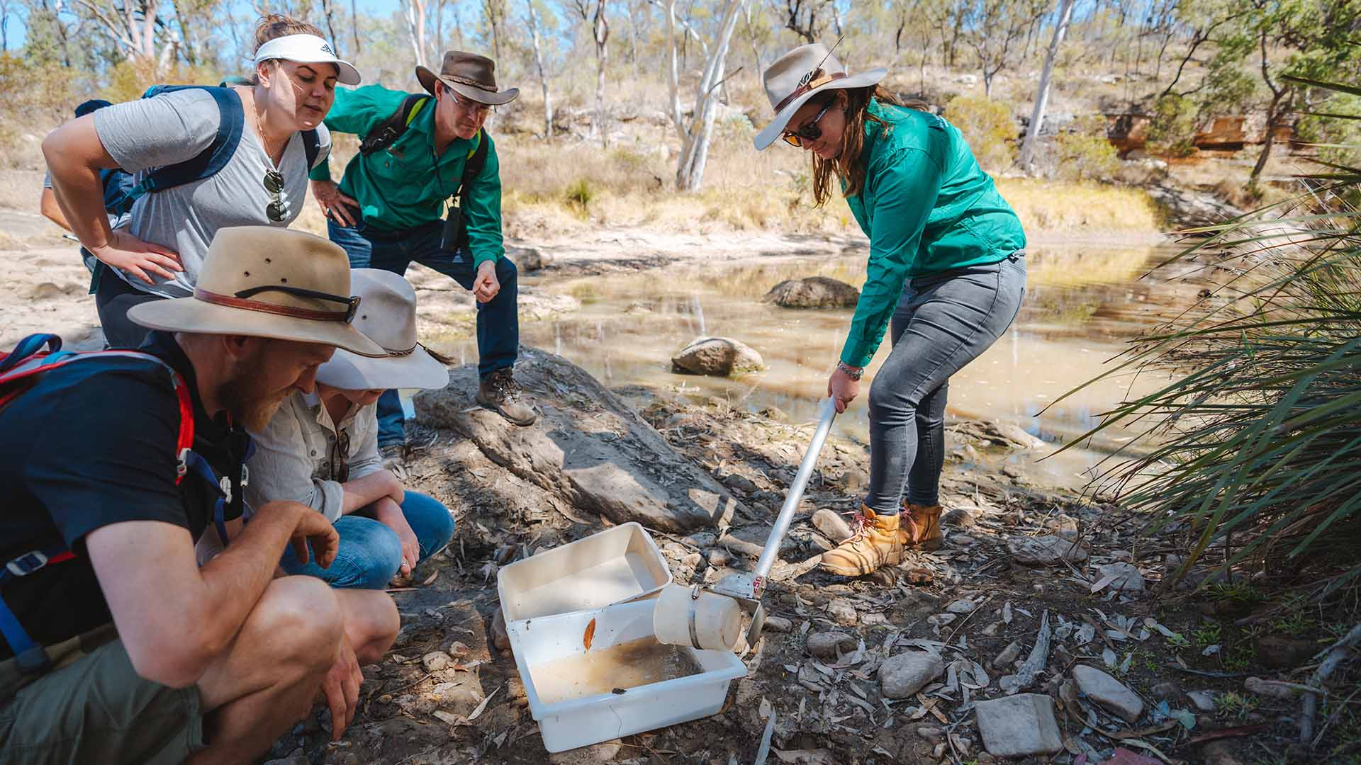 Four people crowded around and studying river water