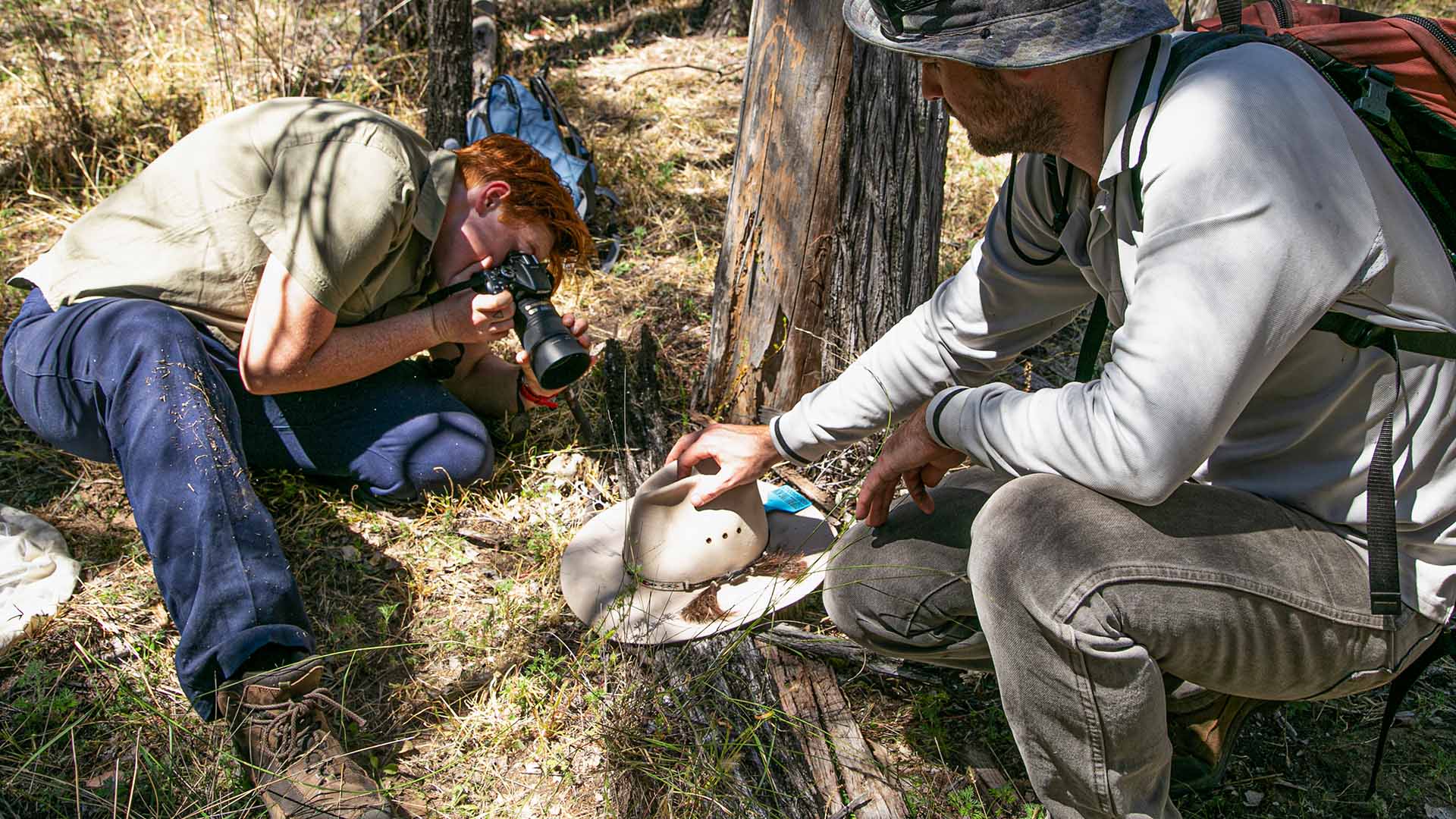 A man getting a close-up photograph while another man watches