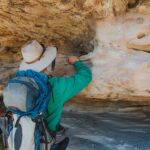 A tour guide pointing to something in a cave for a guest