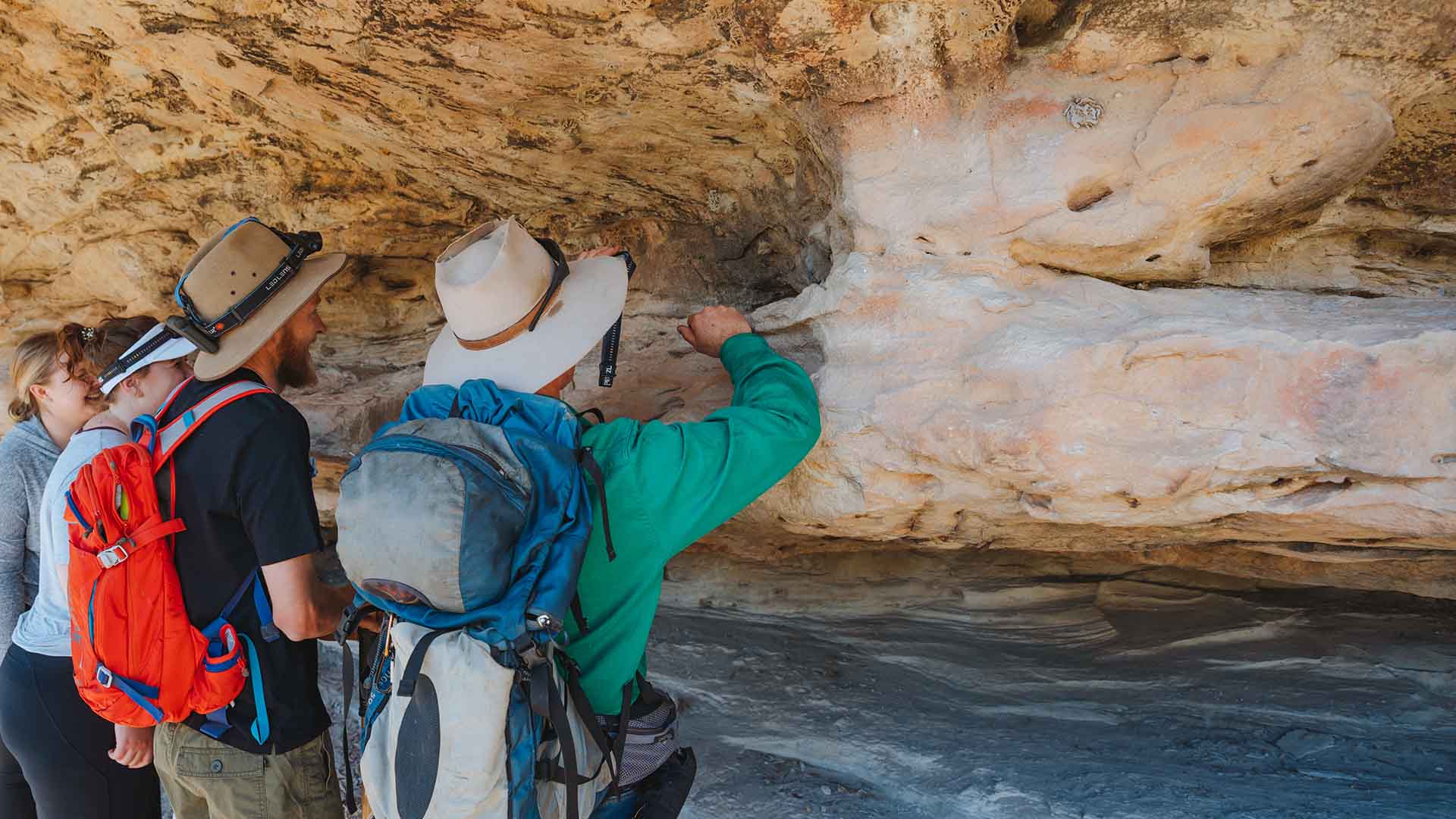 A tour guide pointing to something in a cave for a guest