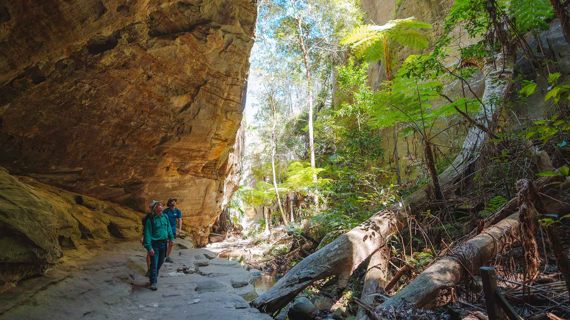 Two people walking underneath a rocky structure