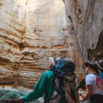 Three people looking up towards an opening in a cave