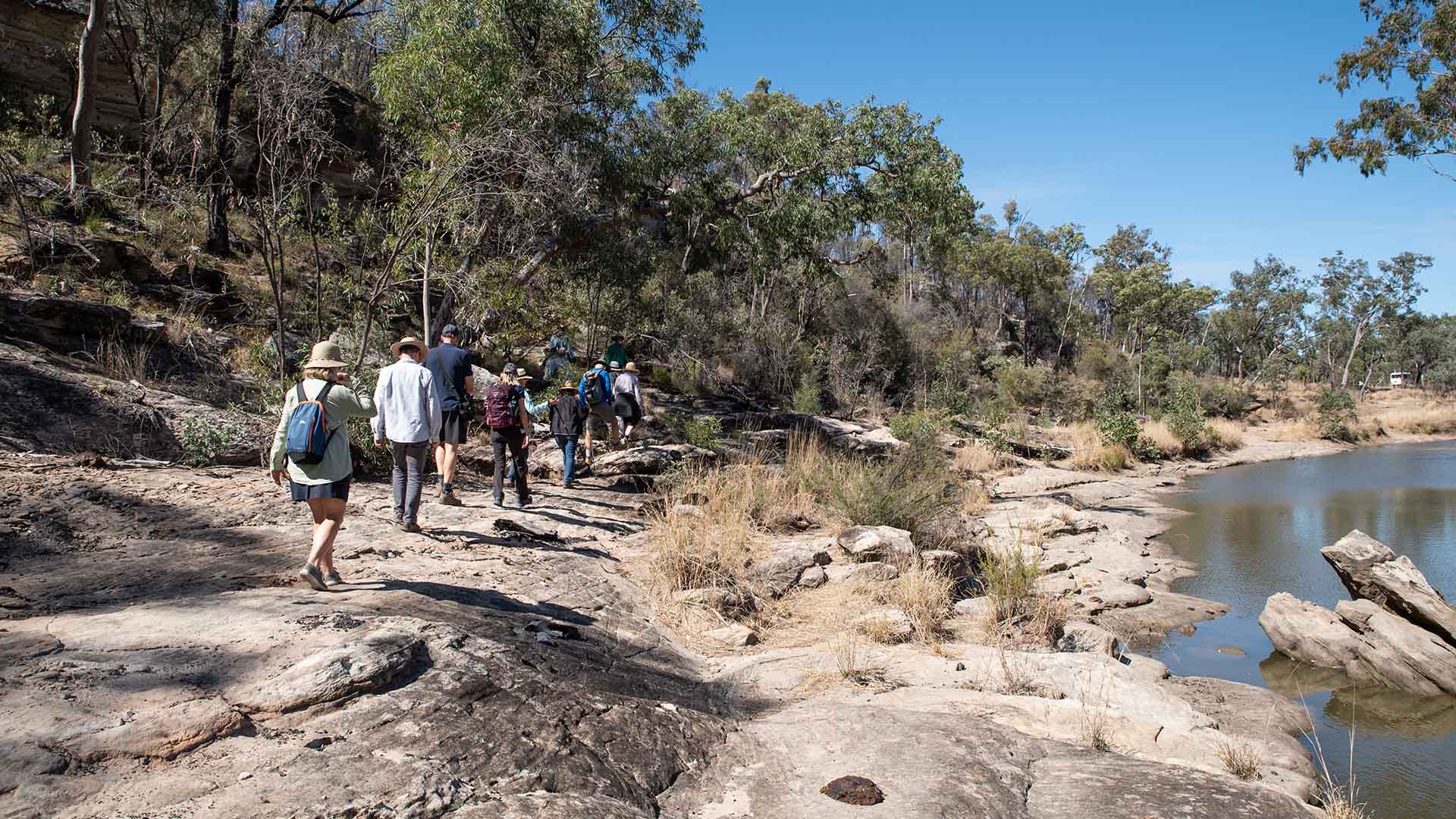 A group of people walking along a riverbank