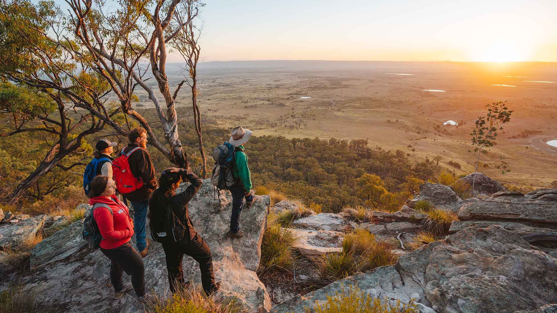 A group of people standing at the edge of a cliff looking out to the valley below