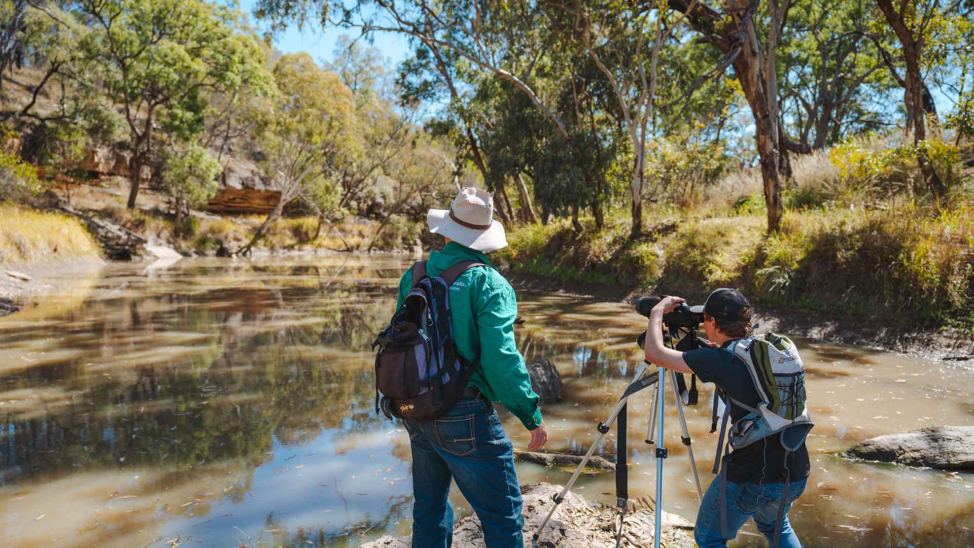 A man standing next to another man taking a photo of the river