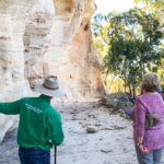 A tour guide showing guests a sandstone rock face