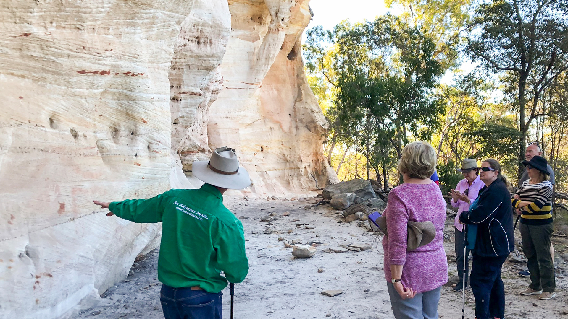 A tour guide showing guests a sandstone rock face