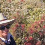 Rose Aisthorpe botanist smiling amongst a field of wildflowers