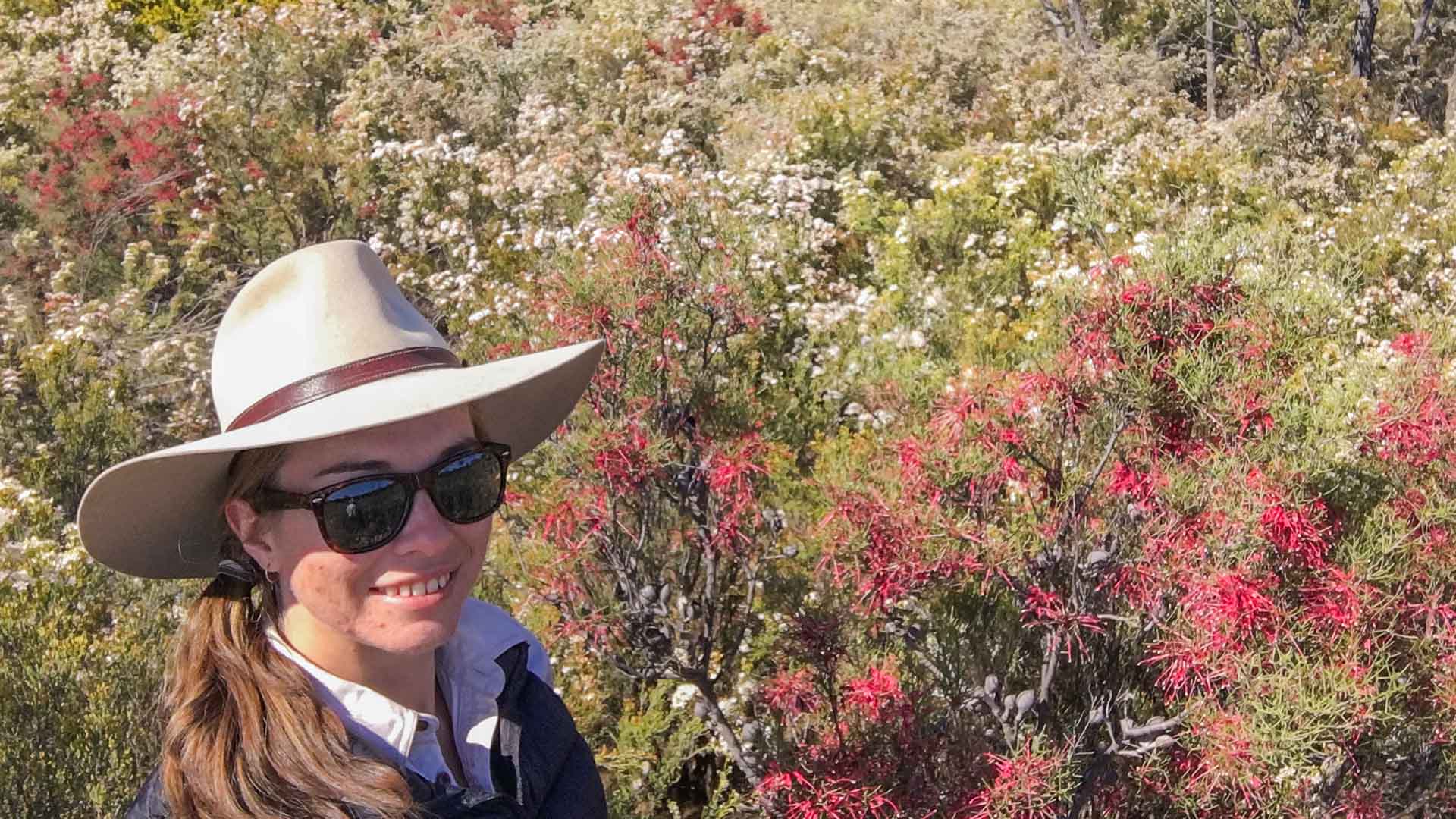 Rose Aisthorpe botanist smiling amongst a field of wildflowers