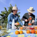 Two people doing a demonstration of pressing oranges