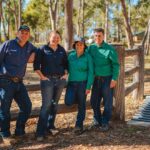 Four people leaning on a fence