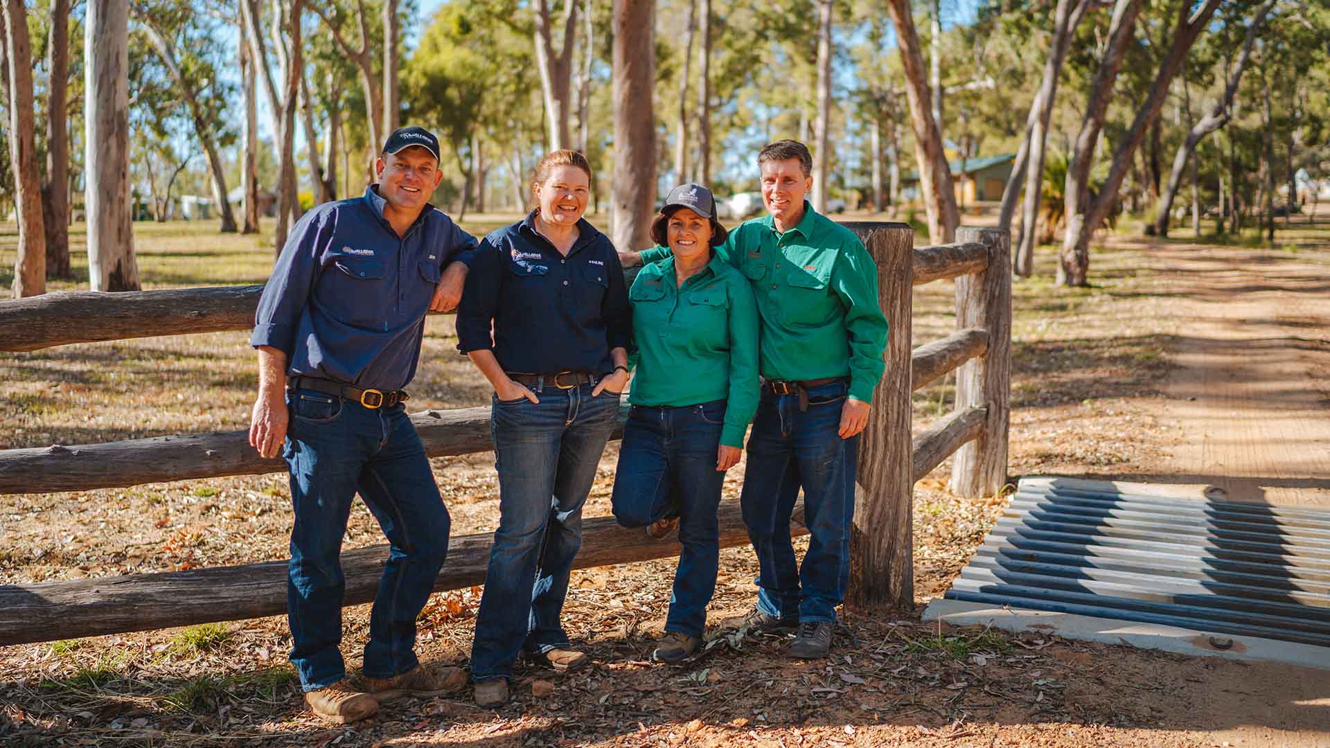 Four people leaning on a fence